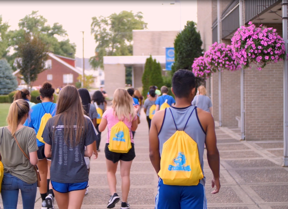 Group of 学生 walking outside of the Moore Center in the Quad.